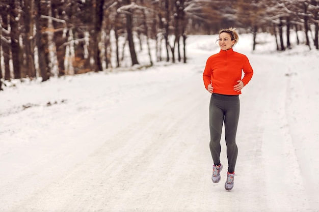 Deportista corriendo en la naturaleza en un día de invierno cubierto de nieve