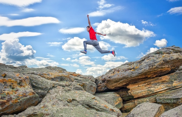 Foto deportista corriendo, saltando por encima de las rocas en la zona de montaña.