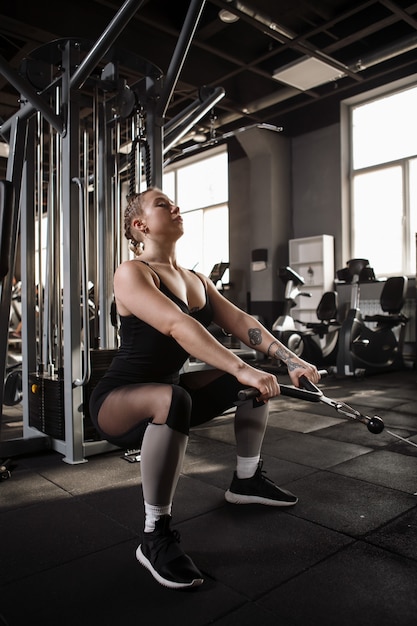 Deportista en cuclillas en máquina de gimnasio crossover