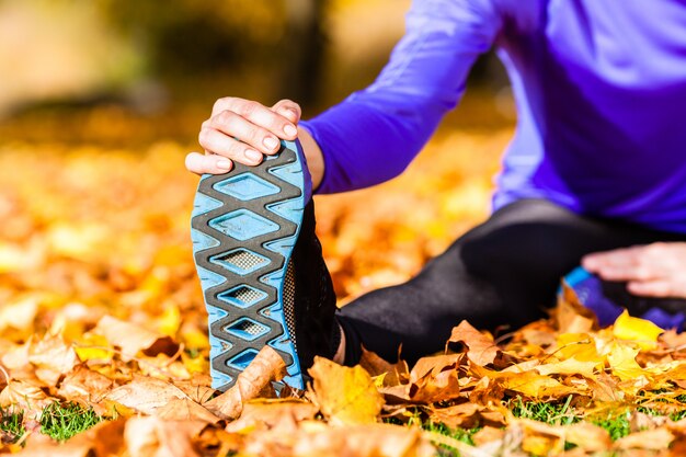 Deportista deportivo estiramiento en hojas otoñales