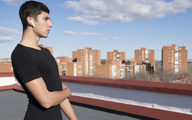 Deportista deportivo fuerte en ropa deportiva entrenamiento de calentamiento hacer ejercicio de estiramiento en un techo escuchando