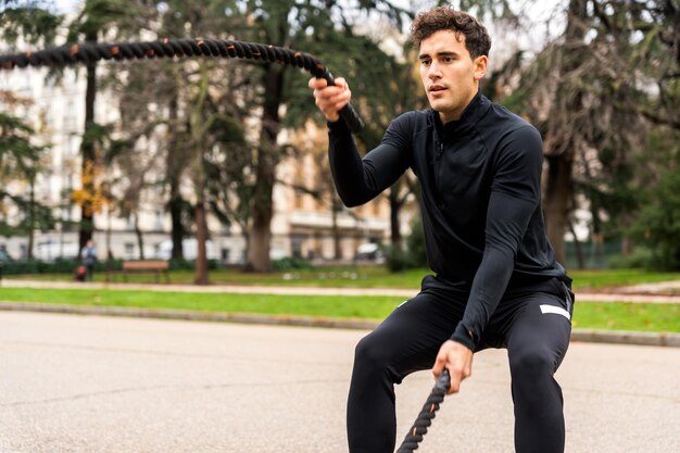 Deportista enfocado entrenando con cuerdas en el parque