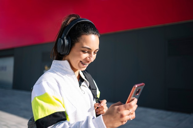 Deportista escuchando música con auriculares en la calle caminando