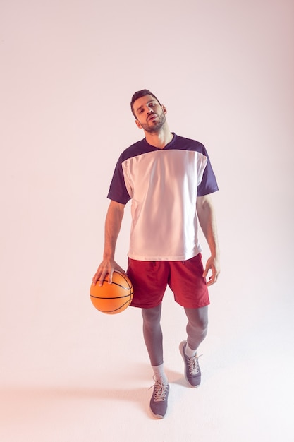 Deportista europeo con pelota de baloncesto en estudio