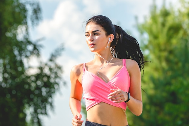 La deportista feliz corriendo con auriculares.