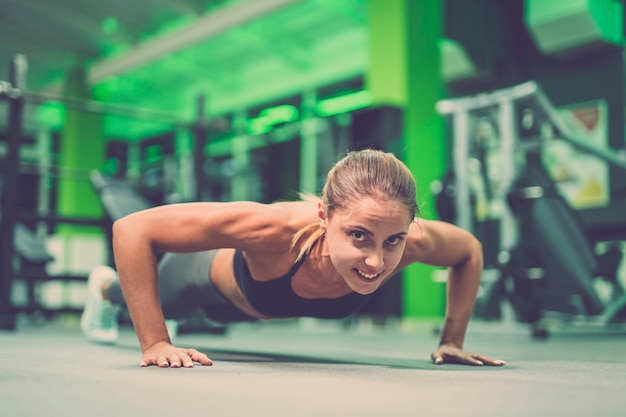 La deportista feliz haciendo ejercicio push up en el gimnasio