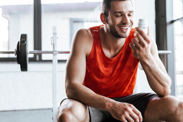 Deportista feliz mirando la botella con letras probióticas en el gimnasio