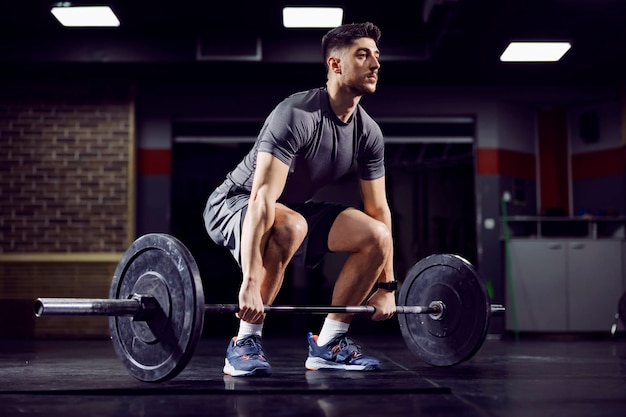 Deportista en forma haciendo peso muerto en el gimnasio y practicando entrenamiento funcional