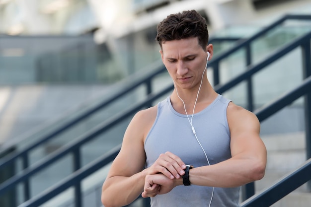 Deportista guapo configuró la aplicación de fitness con reloj inteligente.