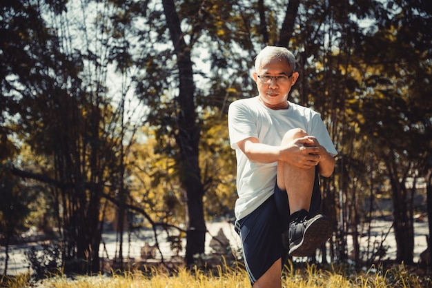 Deportista guapo senior haciendo ejercicios de yoga de estiramiento y equilibrio en el parque. Cómo mantenerse saludable en el concepto de parque.