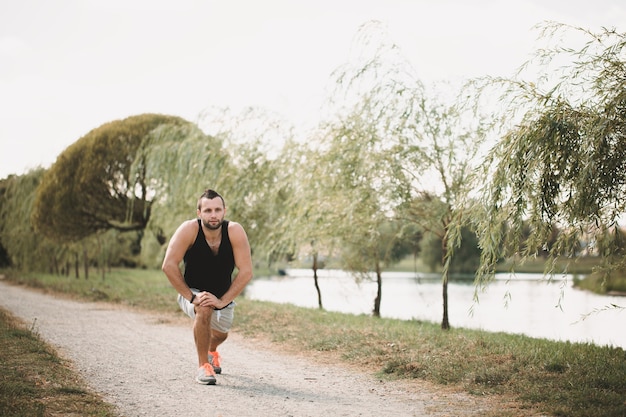 Foto deportista hace ejercicios en la calle. atleta cansado en ropa deportiva hacer una pausa.