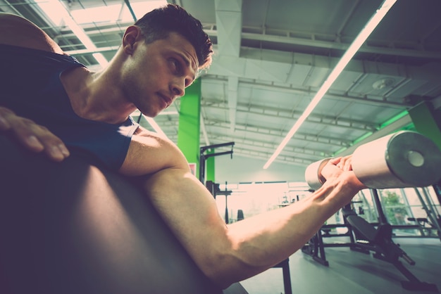 El deportista haciendo ejercicio de bíceps con mancuernas en el gimnasio.