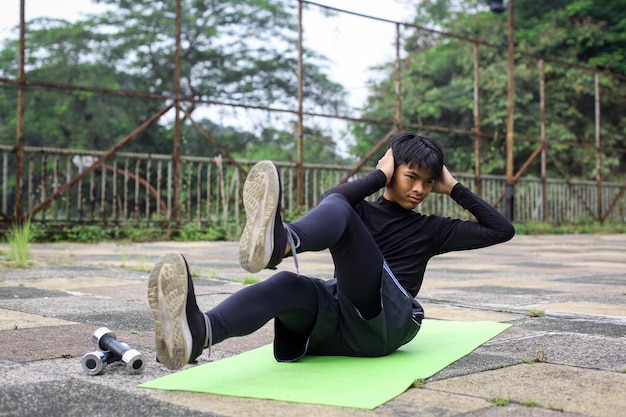 Deportista haciendo ejercicios abdominales con piernas levantadas al aire libre