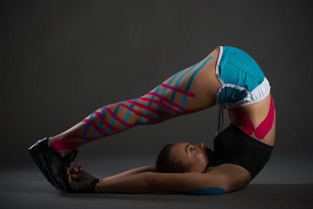Deportista haciendo ejercicios de flexibilidad con pegatinas en las piernas