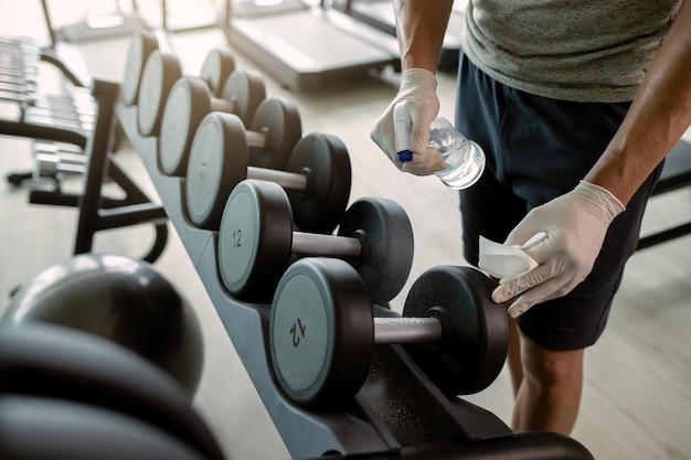 Deportista irreconocible desinfectando pesas de mano en un gimnasio