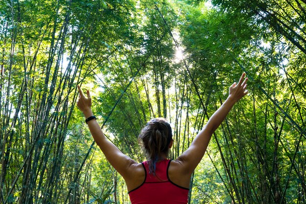 Deportista joven y sana con los brazos abiertos abiertos en medio de la jungla