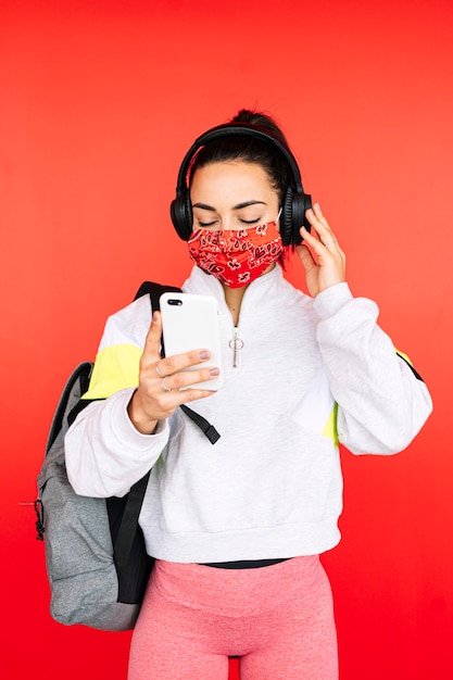 Deportista en máscara escuchando música con auriculares y teléfonos inteligentes.