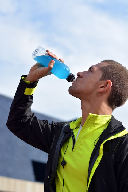 Deportista masculino para beber una bebida isotónica.