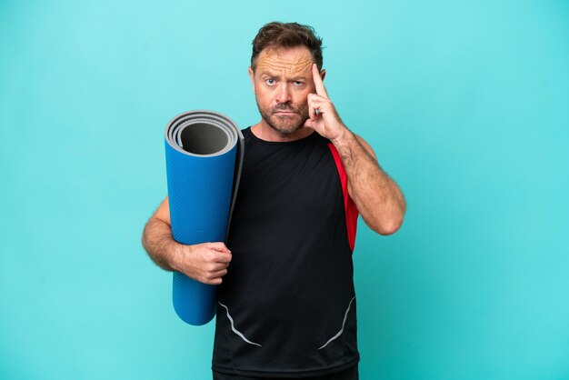 Deportista de mediana edad yendo a clases de yoga mientras sostiene una colchoneta