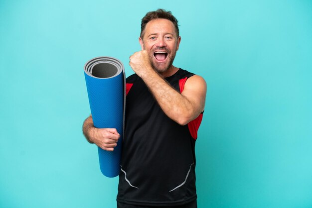 Deportista de mediana edad yendo a clases de yoga mientras sostiene una colchoneta