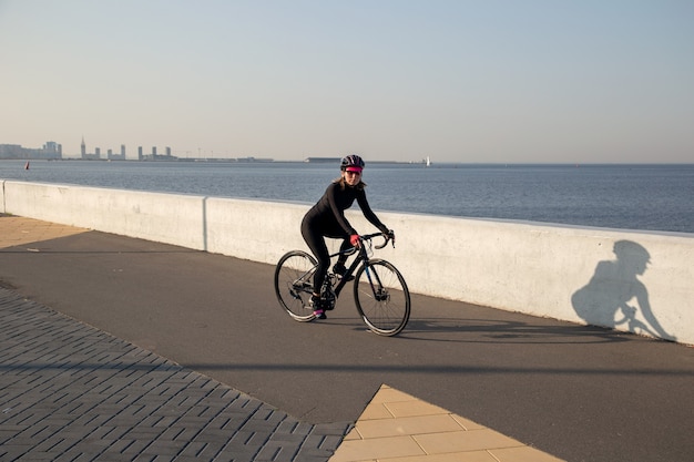 Deportista monta una bicicleta a lo largo del terraplén de la bahía