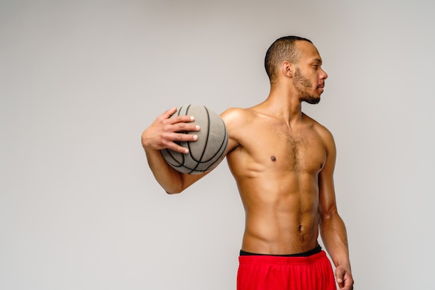 Foto deportista musculoso jugando baloncesto shitless sobre pared gris claro