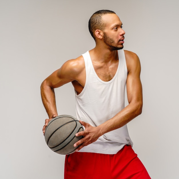 Foto deportista musculoso jugando baloncesto sobre pared gris claro