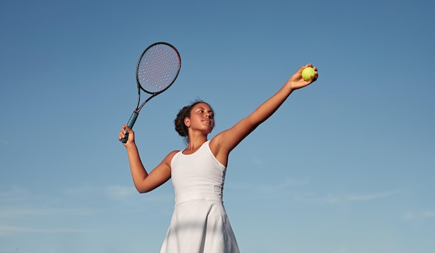Deportista negra jugando tenis contra el cielo azul
