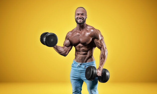 Deportista profesional aislado sobre un fondo amarillo. Concepto de culturismo. Panorama. Publicidad de un gimnasio y nutrición deportiva. Técnica mixta