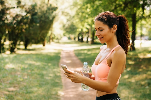 Deportista que descansa después de entrenar de la aptitud y usar smartphone.