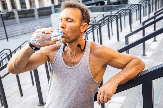 Foto deportista sediento tomar un descanso y beber agua después de correr