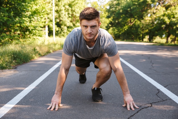 Deportista seguro listo para comenzar a correr en una carretera