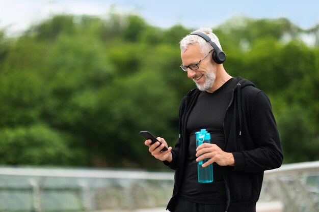 Deportista senior corriendo al aire libre escuchando música copiando espacio