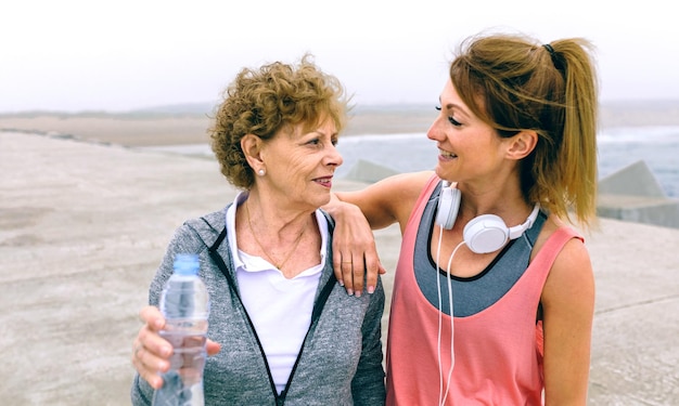 Deportista senior hablando con una amiga por el muelle del mar