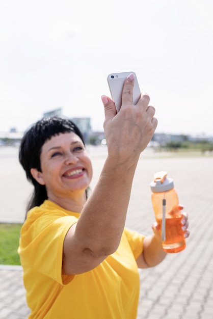 Deportista senior sonriente haciendo selfie al aire libre en el parque