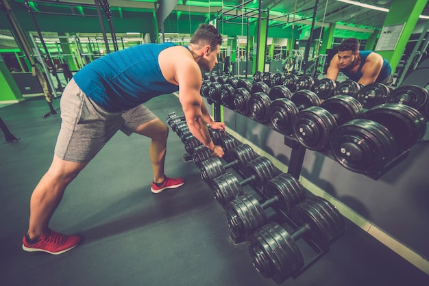 El deportista toma una mancuerna en el gimnasio.