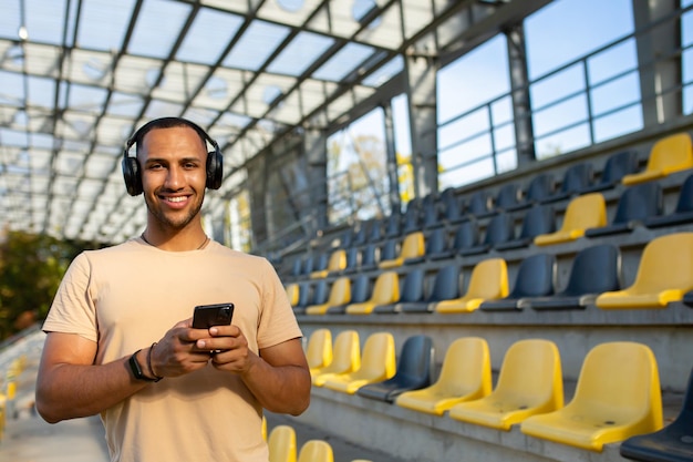 Deportista usando el teléfono sonriendo y mirando a la cámara hombre corriendo por la mañana y haciendo ejercicio en deportes