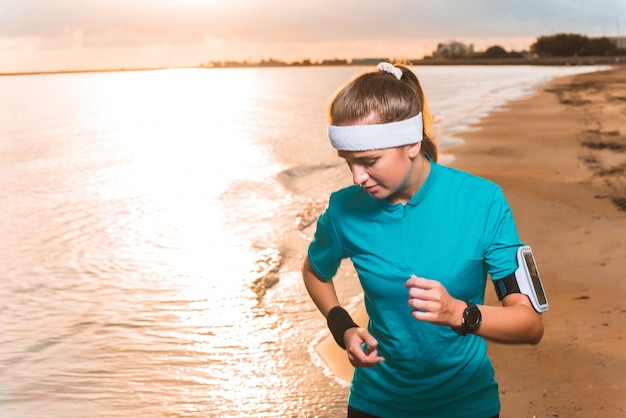 Deportiva joven corriendo en la playa al amanecer en la mañana