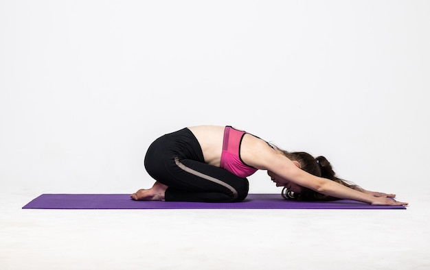 Deportiva joven haciendo práctica de yoga aislado en blanco. Concepto de vida sana y equilibrio natural entre el desarrollo corporal y mental.