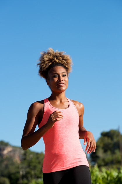 Deportiva joven mujer afroamericana corriendo al aire libre