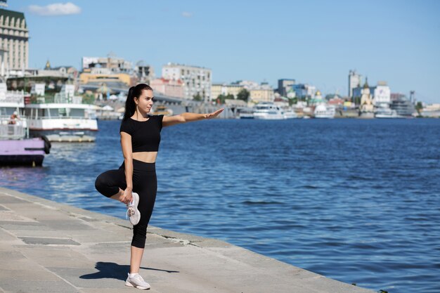 Deportiva joven que se extiende en la calle, cerca del río. Espacio para texto