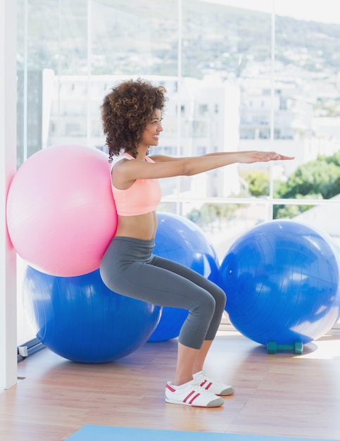 Deportiva mujer con balón de ejercicio en el gimnasio