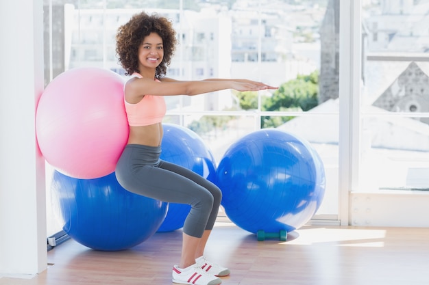 Deportiva mujer con balón de ejercicio en el gimnasio