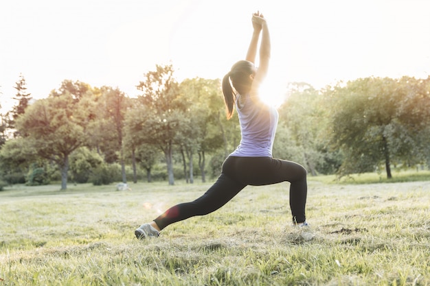 Deportiva mujer calentando antes de hacer ejercicio, yoga o fitness al aire libre al amanecer o al atardecer.