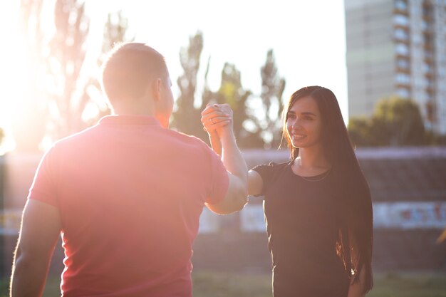 Foto deportiva mujer feliz dando cinco en el estadio. tiro al aire libre con rayos de sol