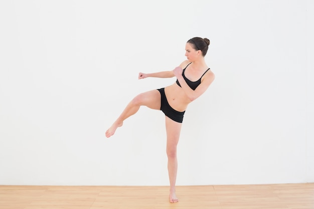 Deportiva mujer fit realizar una patada de aire en el gimnasio