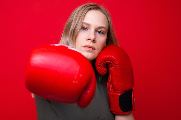 Deportiva mujer joven en guantes de boxeo rojos practicando golpes