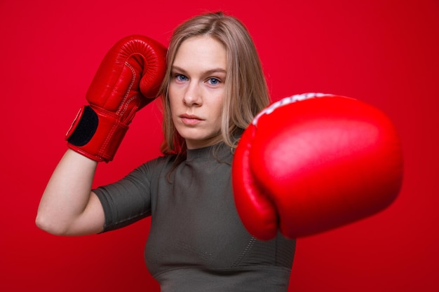 Deportiva mujer joven en guantes de boxeo rojos practicando golpes