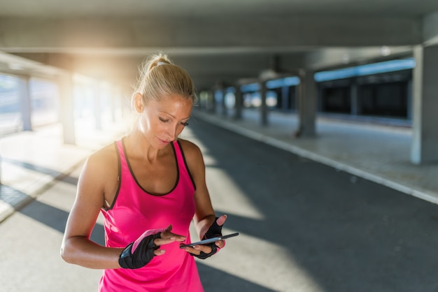 Deportiva mujer joven usando un teléfono