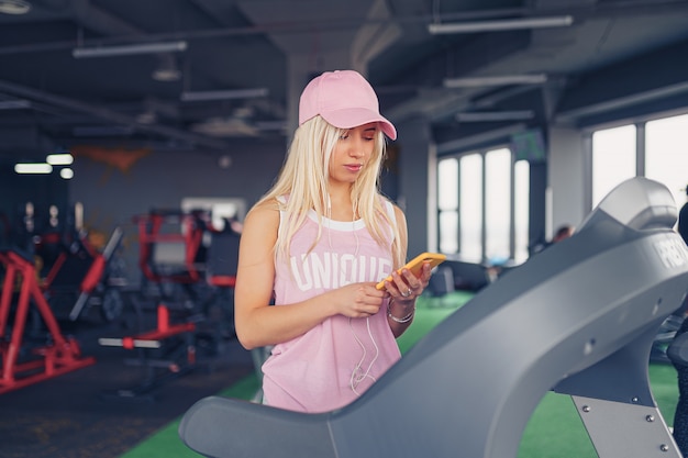 Deportiva mujer rubia haciendo ejercicio en la caminadora en el gimnasio